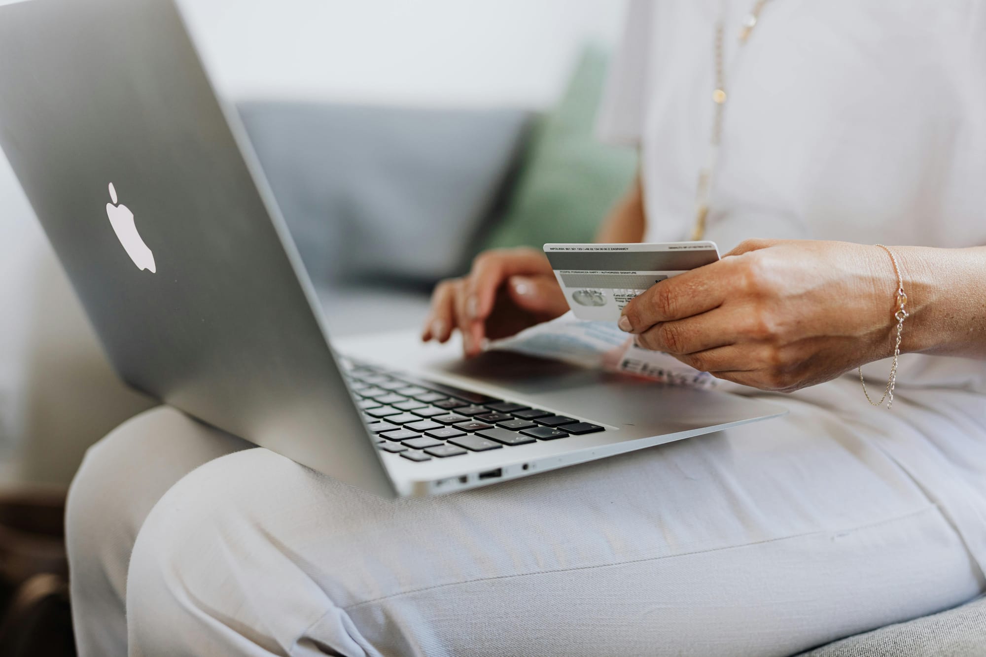 A woman using her macbook and holding a credit card