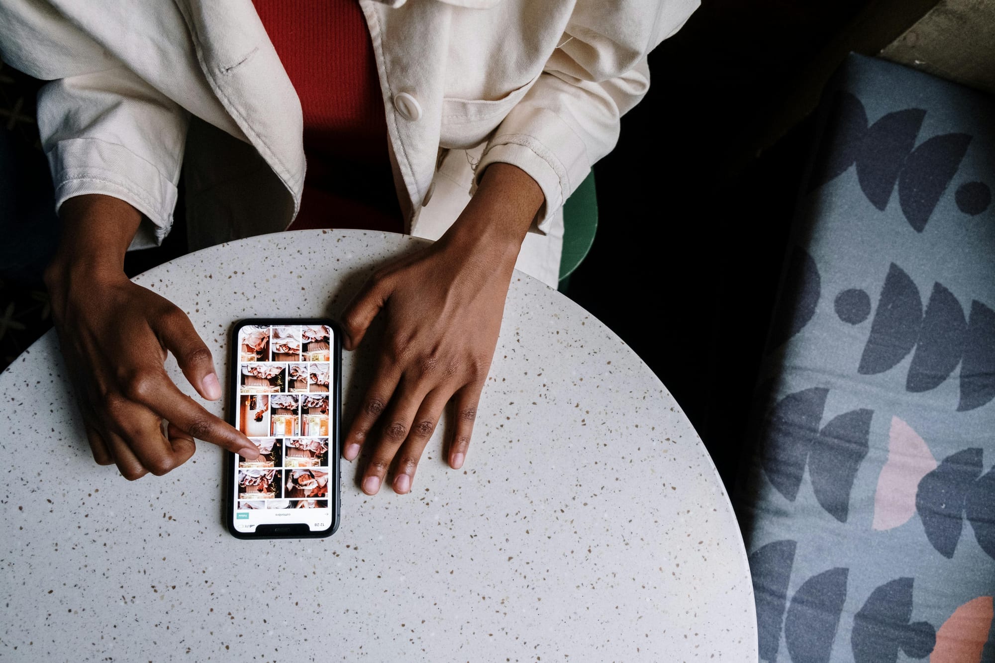 Person in white jacket holding a phone, scrolling on Instagram