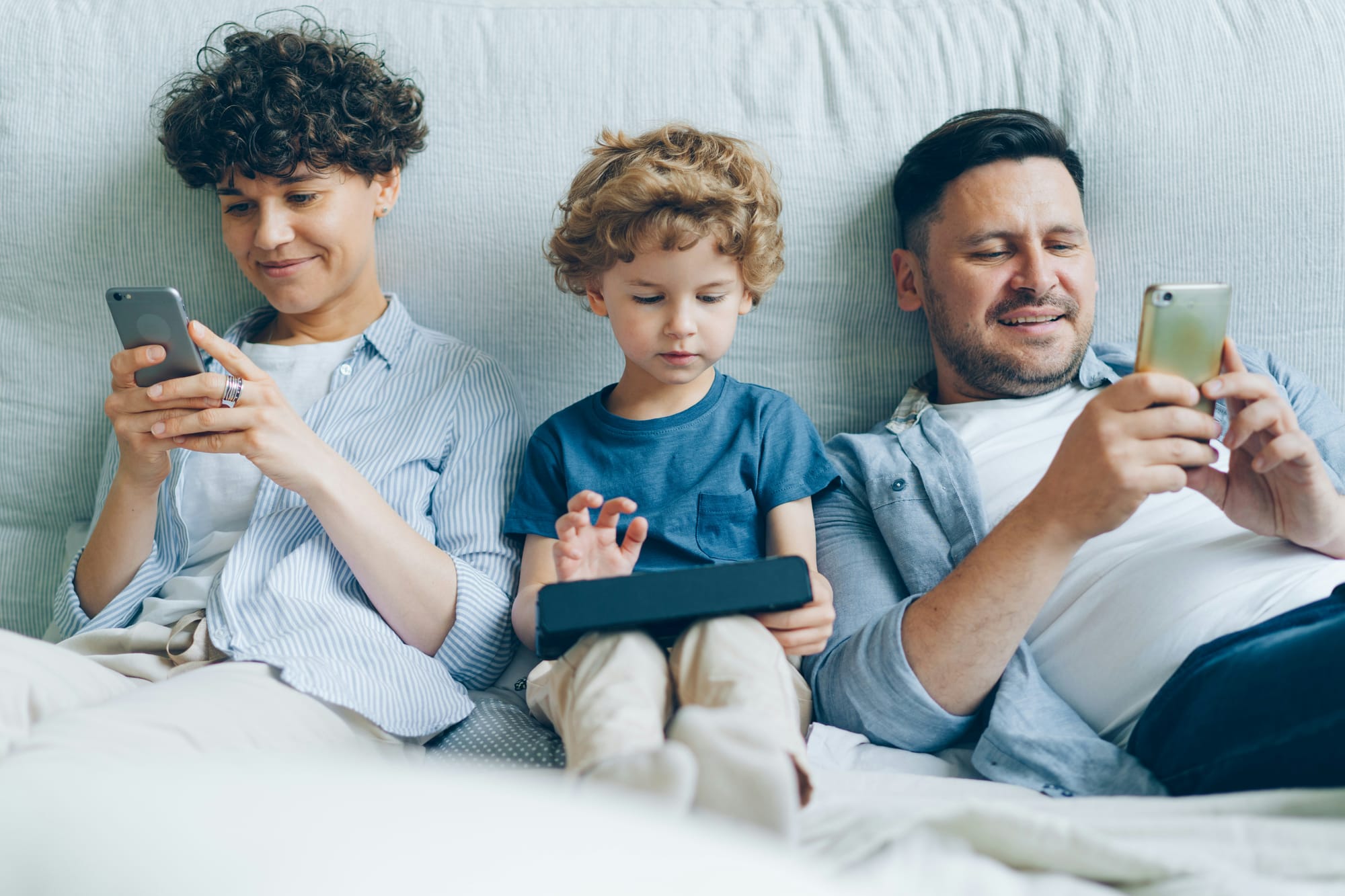 A man, woman and child on their mobile phones 